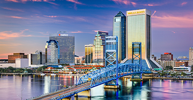 Pictured: A cityscape of Jacksonville with a bridge during sunset.